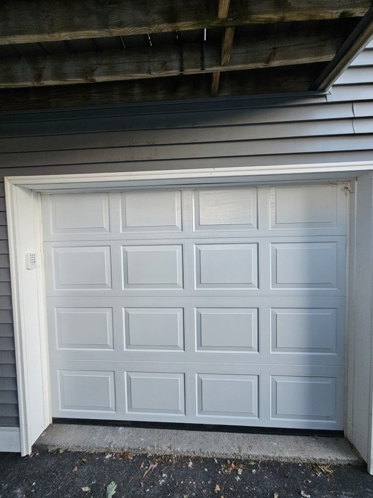 Garage doors after replacement — new white door on a navy-sided home