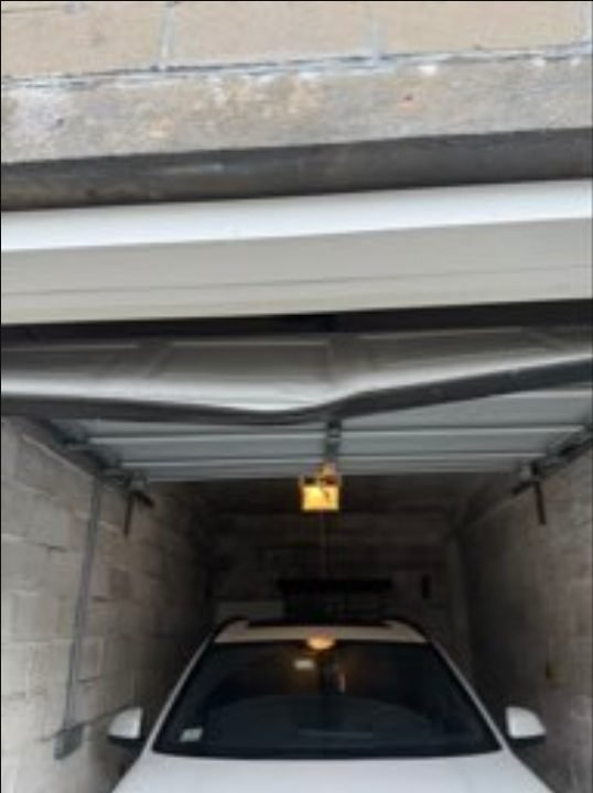 Damaged garage door panel before repair in Belmont, MA